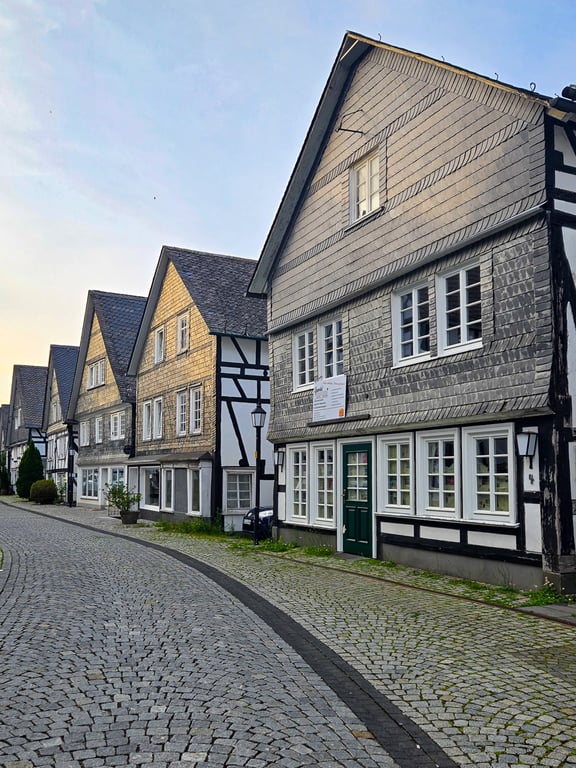 Half-timbered buildings and cobblestone street with a sunset reflection